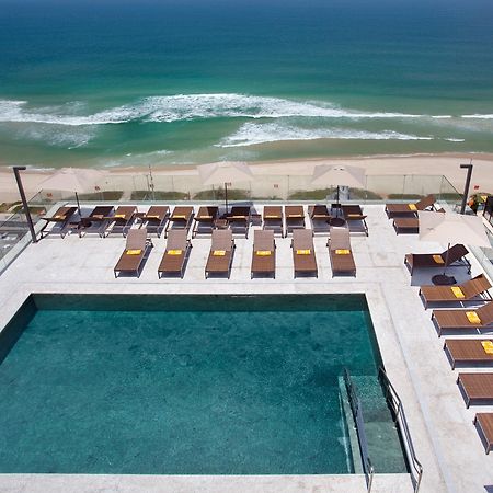 Windsor Marapendi Hotell Rio de Janeiro Exteriör bild The photo shows a rooftop area with a swimming pool and several lounge chairs arranged around it. The pool has a clear blue surface, and the lounge chairs are positioned in a neat row, some with yellow cushions. In the background, you can see a beaut